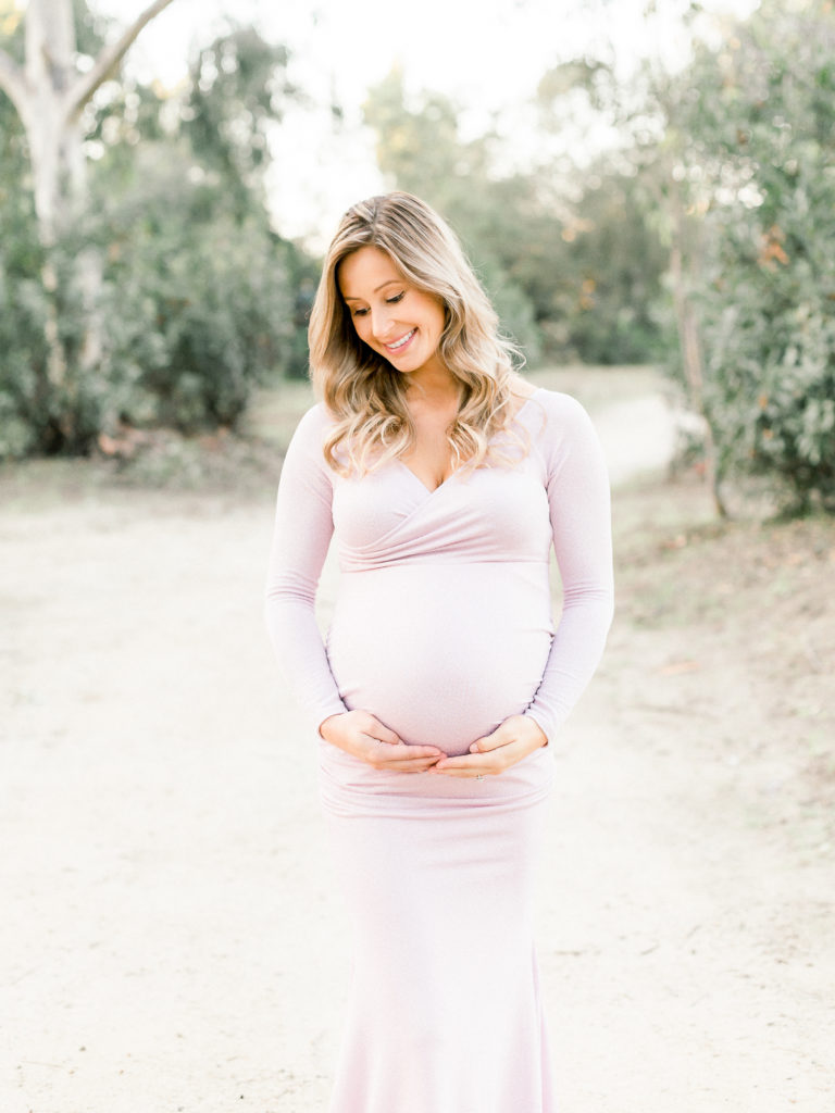 Pregnant lady smiling while holding her baby bump during her maternity session