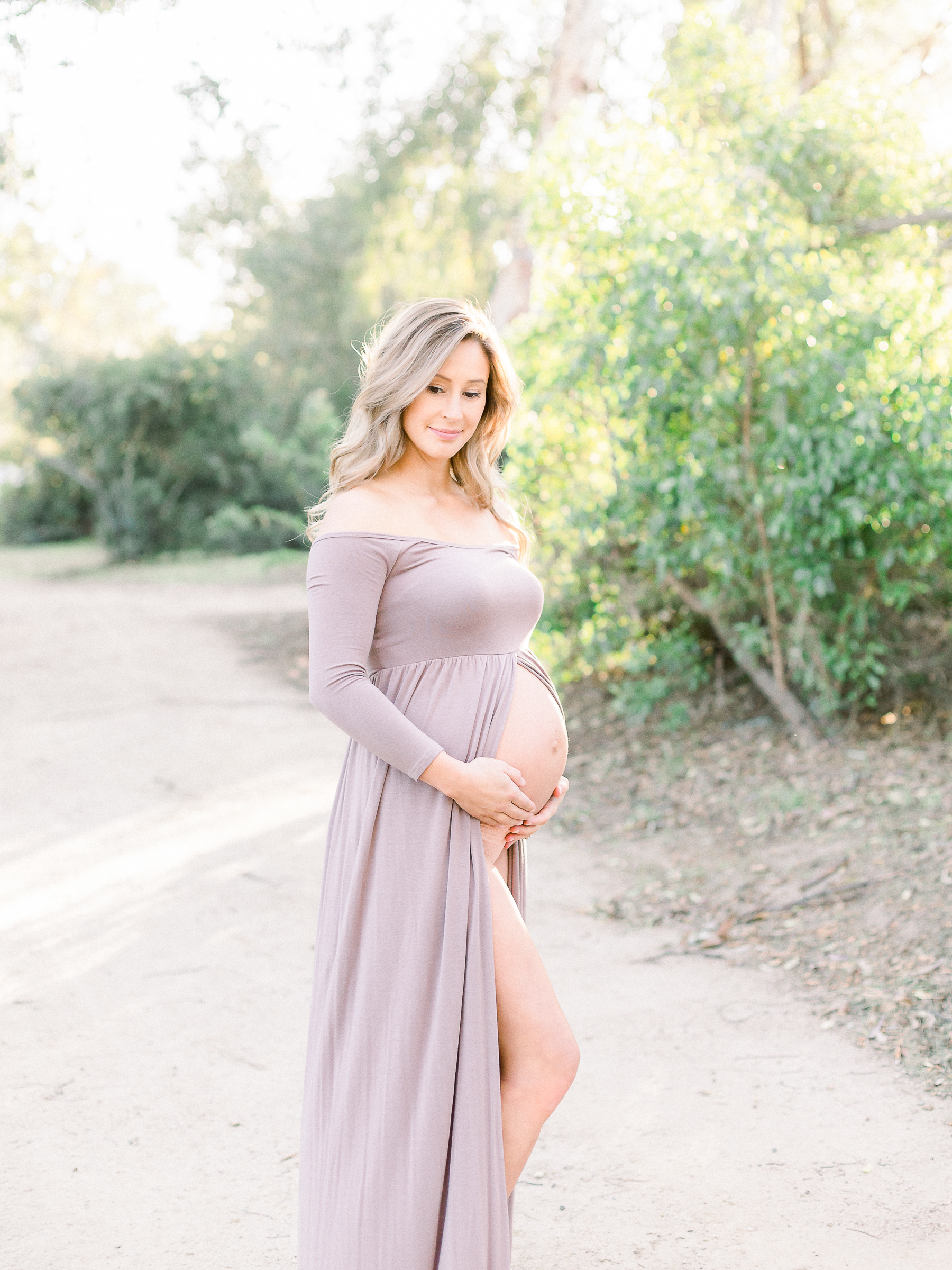 Pregnant woman wearing maternity dress photographed at the park