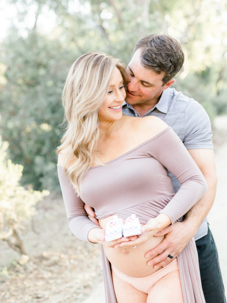 Expecting couple holding baby shoes during their maternity photo session