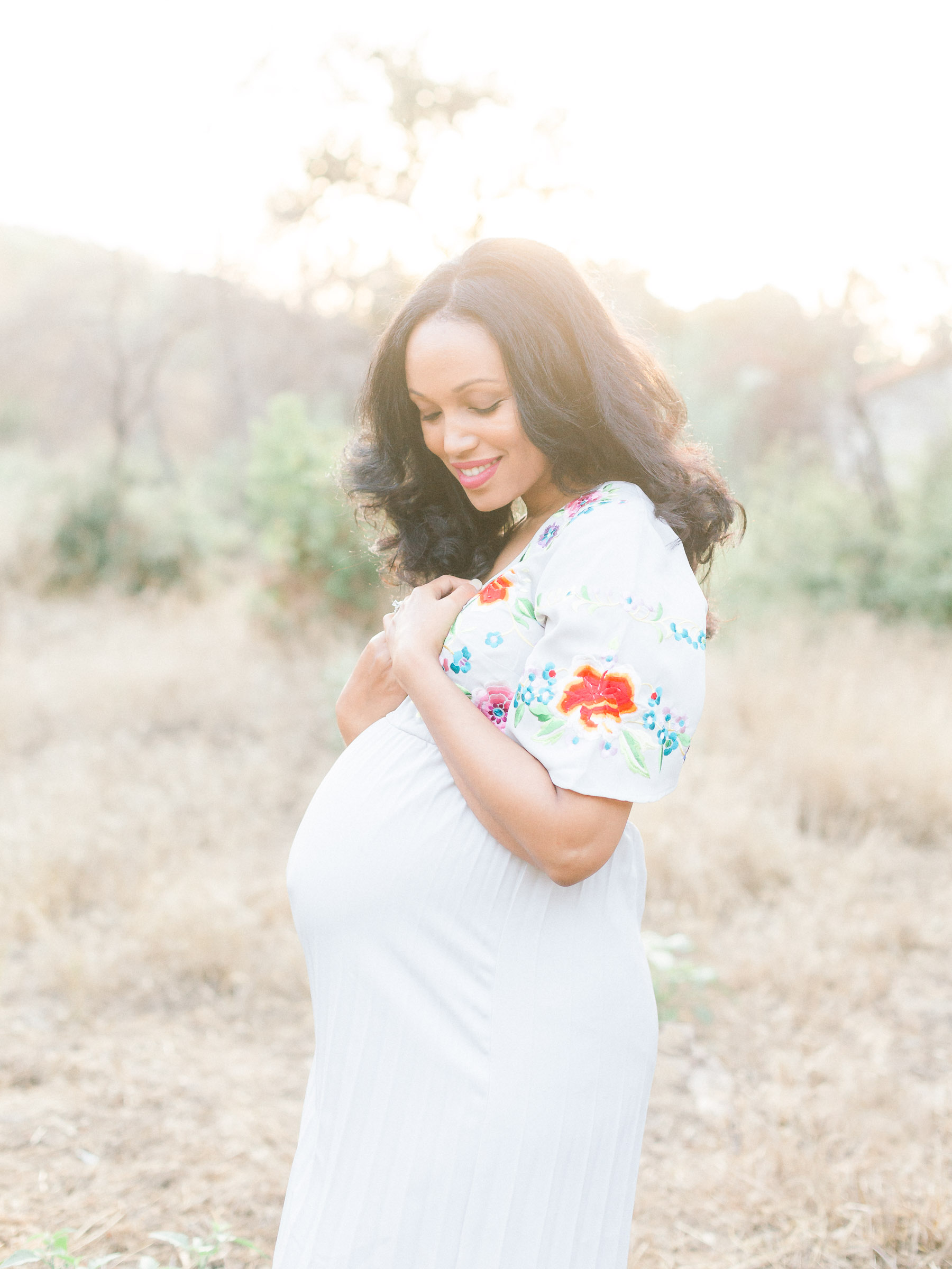 Pregnant lady with hands at her heart smiling down at baby
