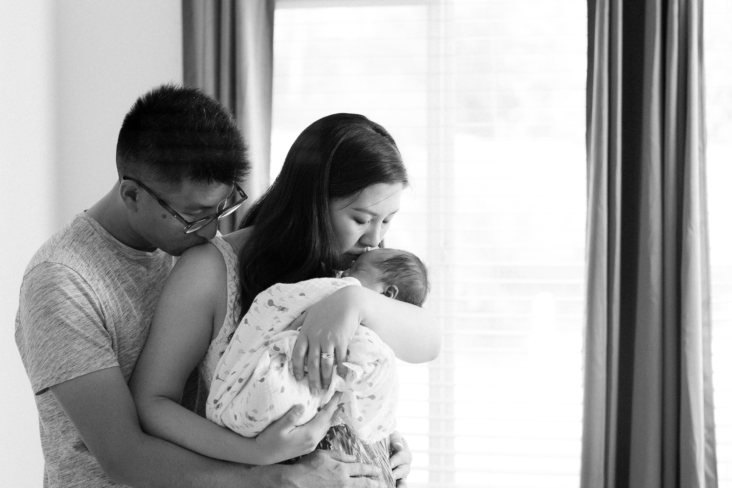 Parents holding newborn baby by the window