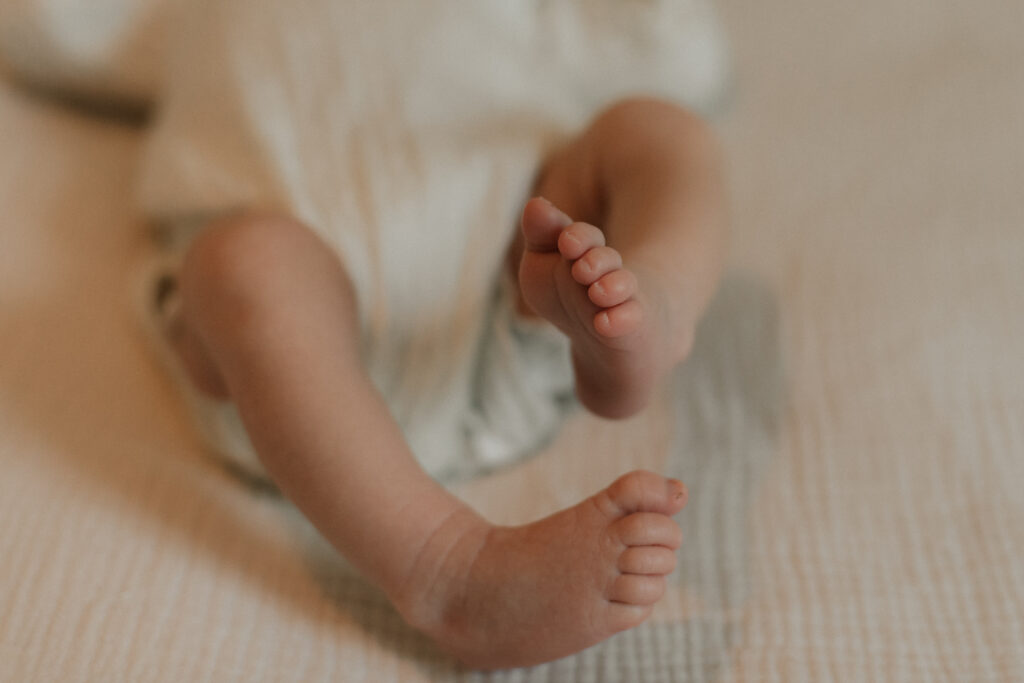 Close-up of newborn’s feet resting on soft blanket during in-home lifestyle baby session