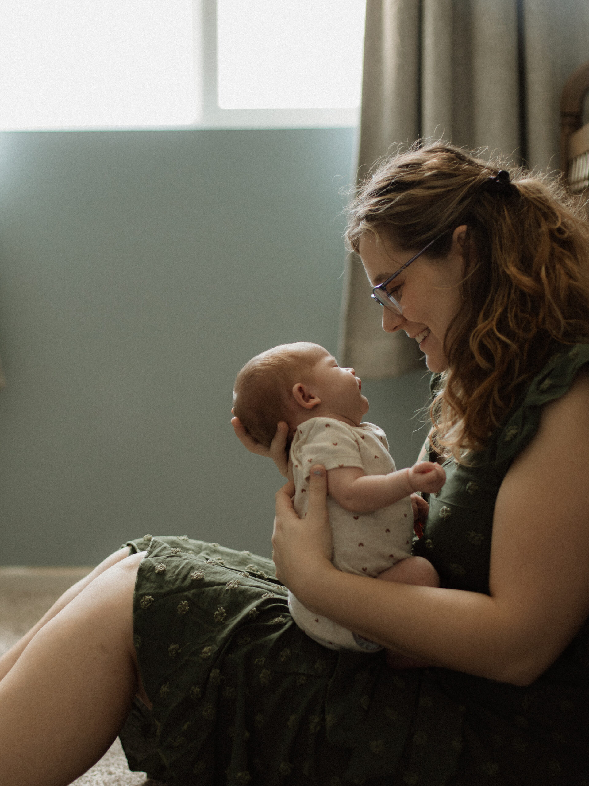 Mother holding newborn on the nursery floor during an in-home session in Hemet, California.