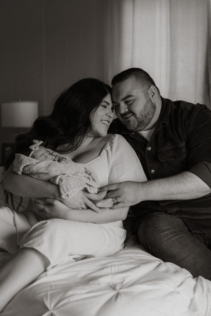 Family cuddled on bed in black and white