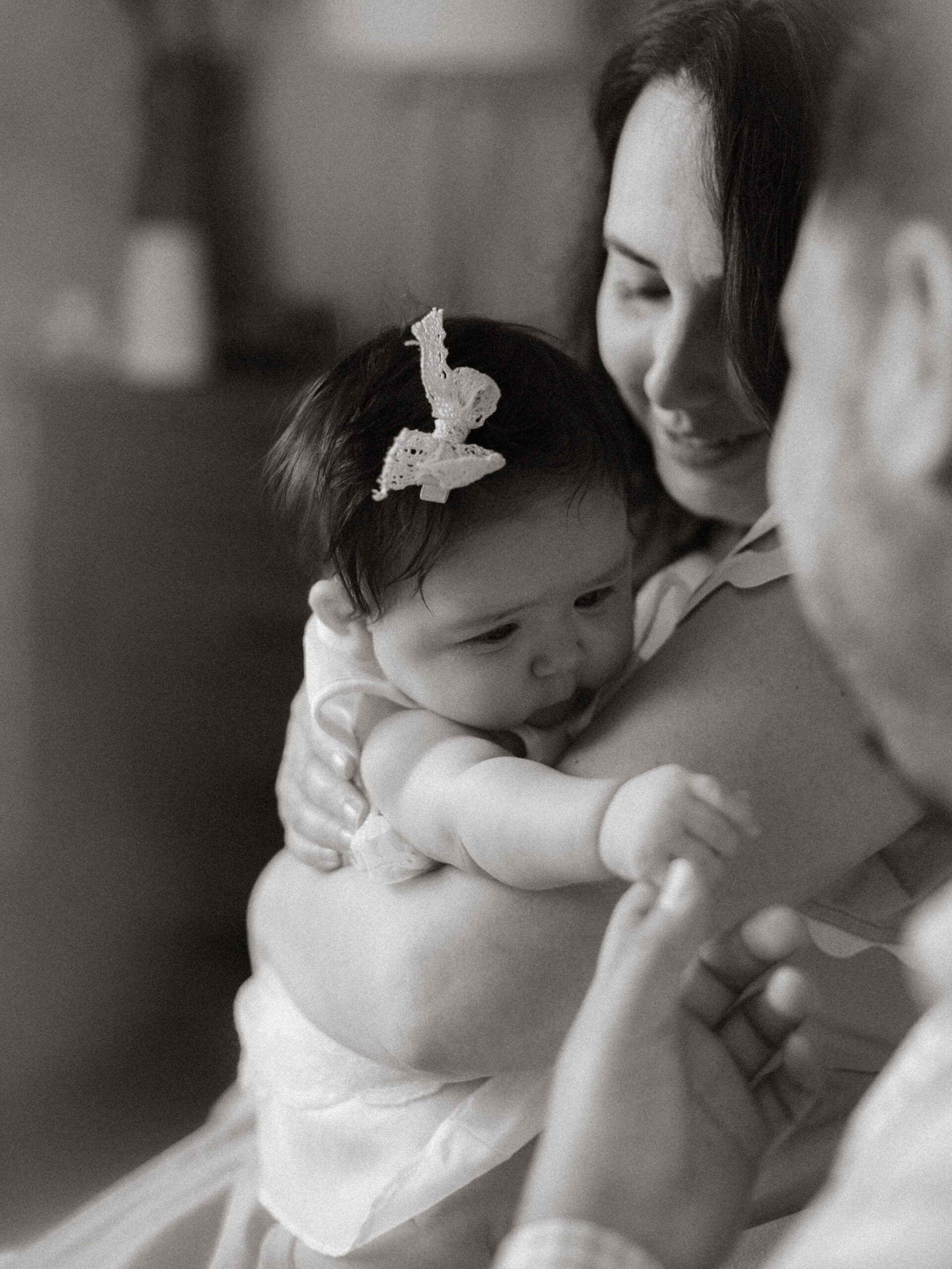 Detailed black and white image of baby’s hair and head cradled by mother during in-home baby photography