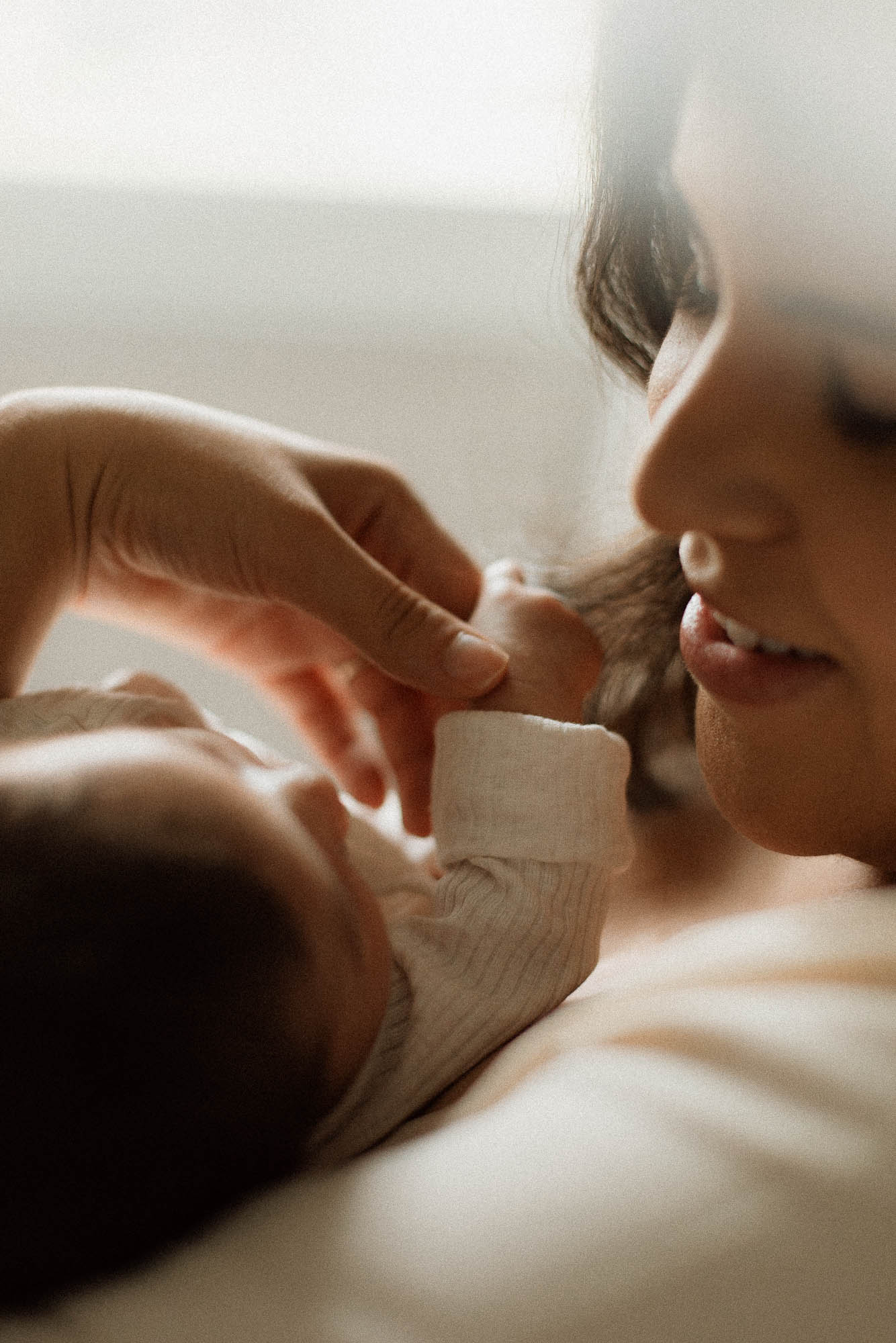 Mom glancing over baby girl while holding her tiny little hand.